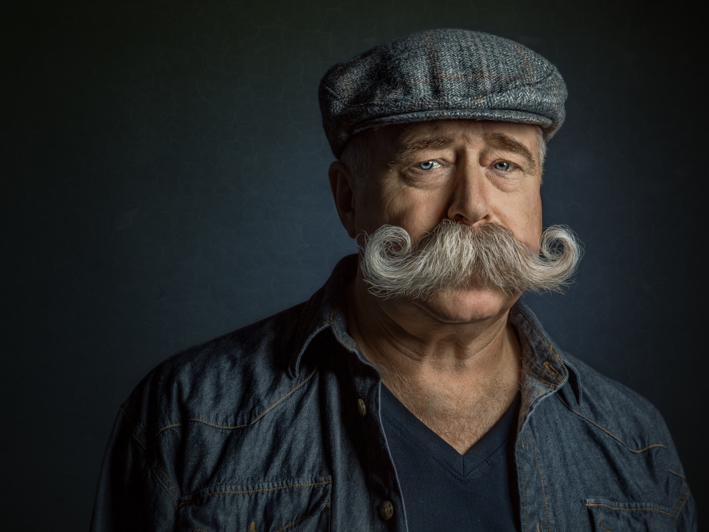 Мужчина в кепке с большими усами на лице 