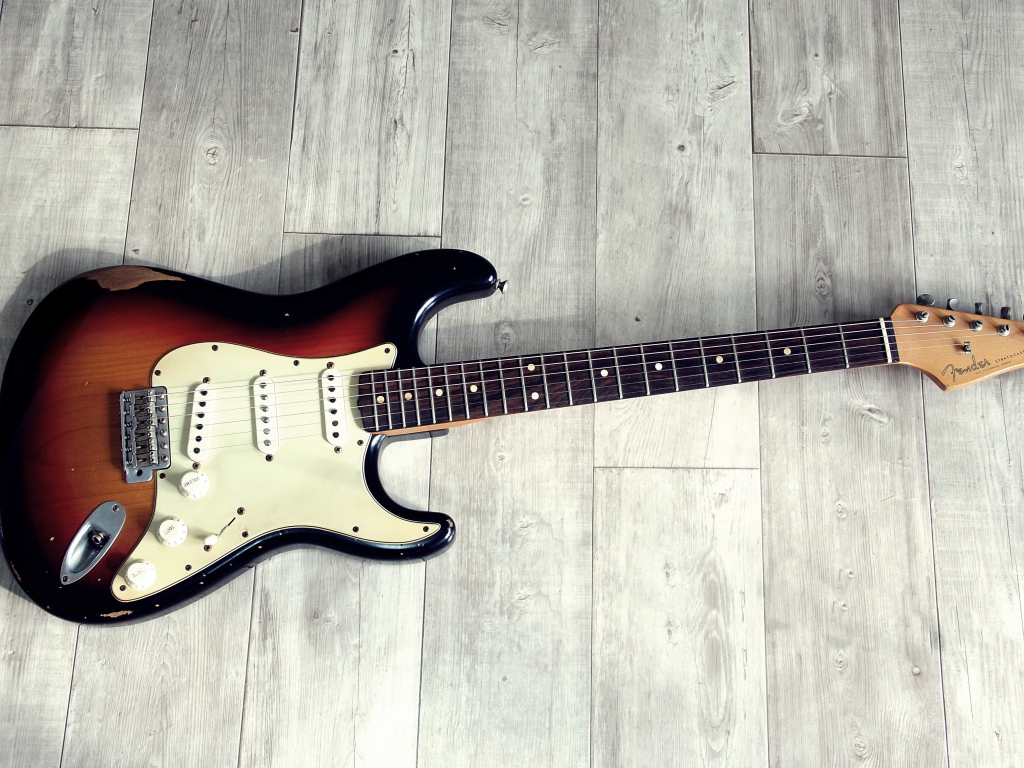 Электрогитара лежит на деревянном полу