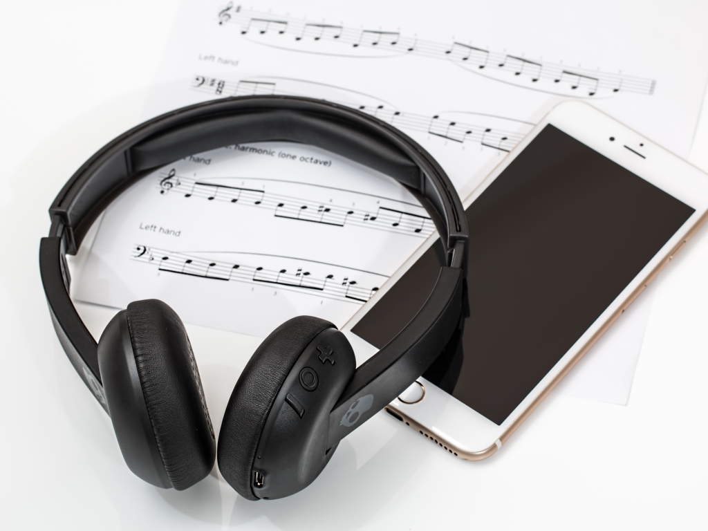 Наушники на столе с нотами и смартфоном
