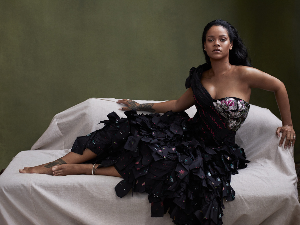 Певица Рианна в черном платье на диване 