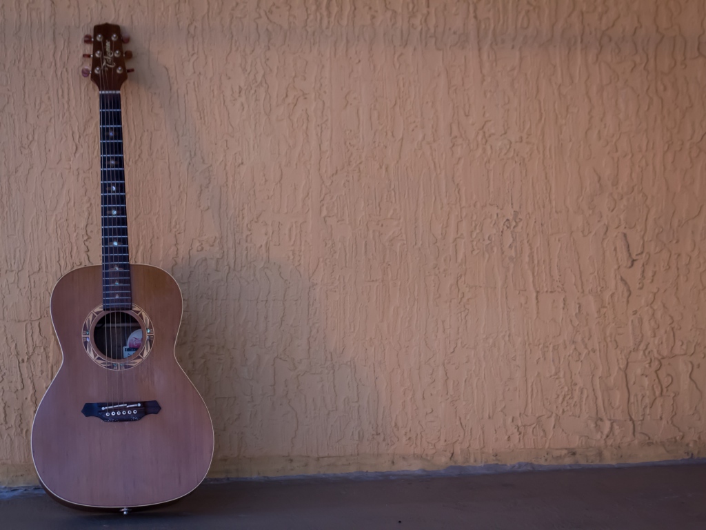 Шестиструнная гитара стоит у стены
