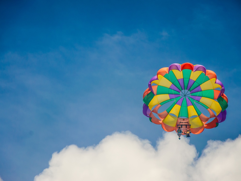 Парашют в голубом небе с белыми облаками
