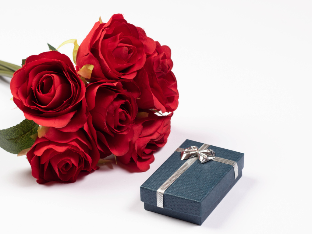 Букет красных искусственных роз с подарком на белом фоне