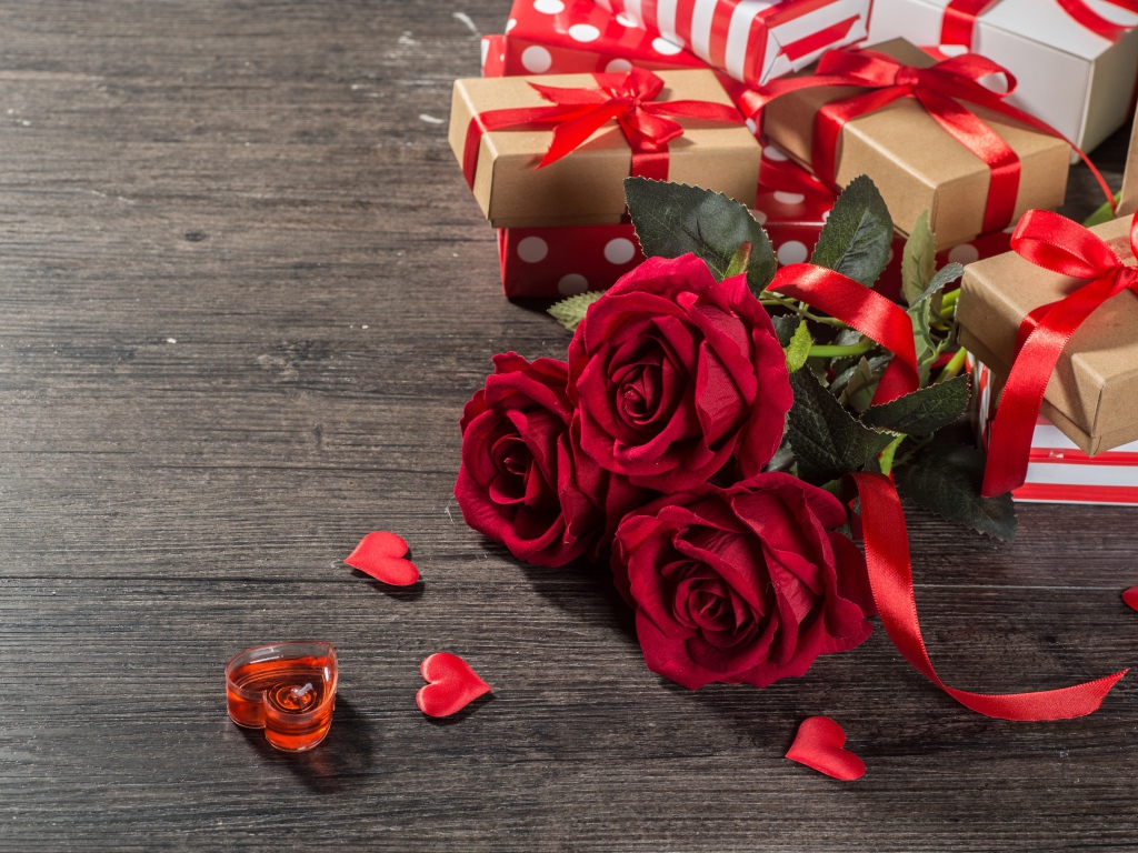 Букет красных роз и подарки на столе 