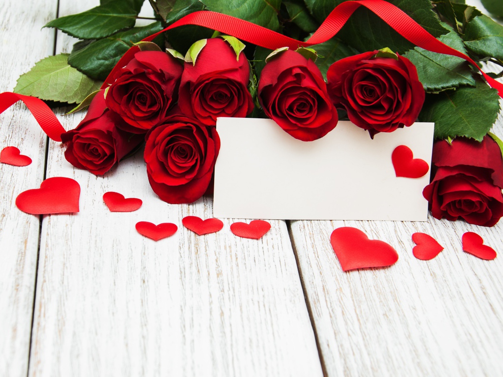 Букет красных роз на столе с сердечками и открыткой