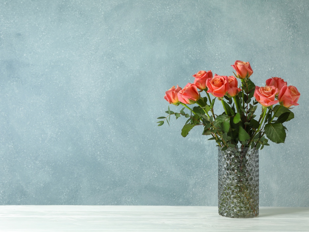 Букет роз в стеклянной вазе на сером фоне