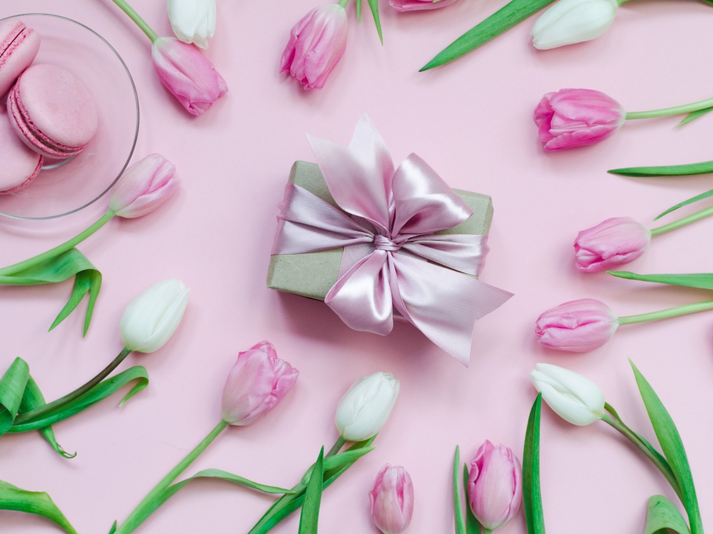 Тюльпаны на розовом фоне с подарком и десертом макарон 