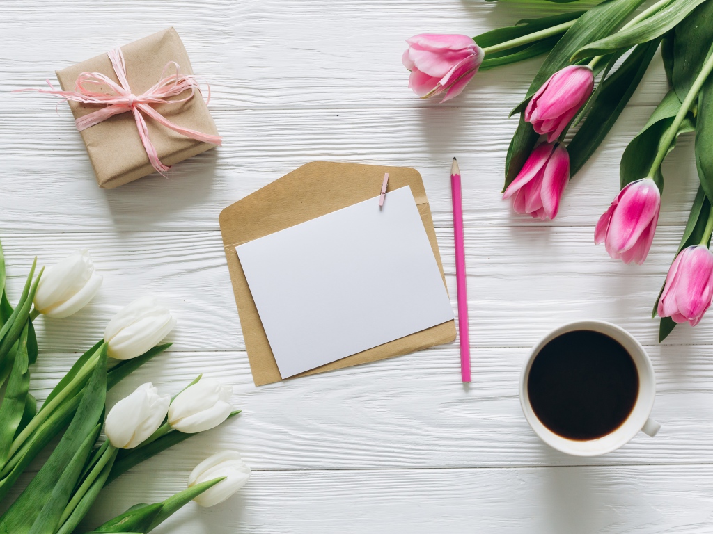 Два букета тюльпанов на столе с подарком, кофе и письмом