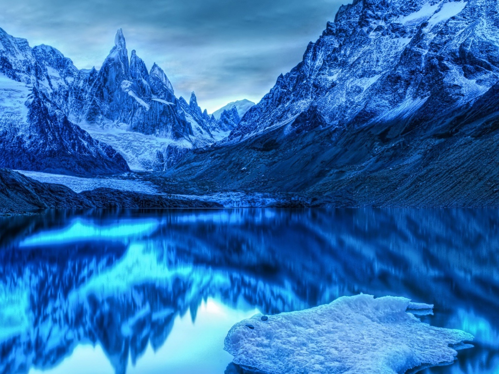 Голубой холодный закат на заснеженными горами у озера 