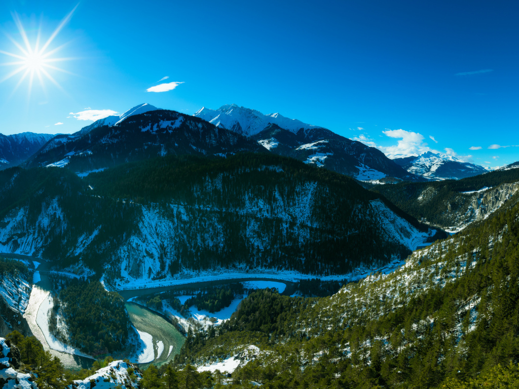 Яркое солнце в голубом небе над заснеженными горами, Швейцария 