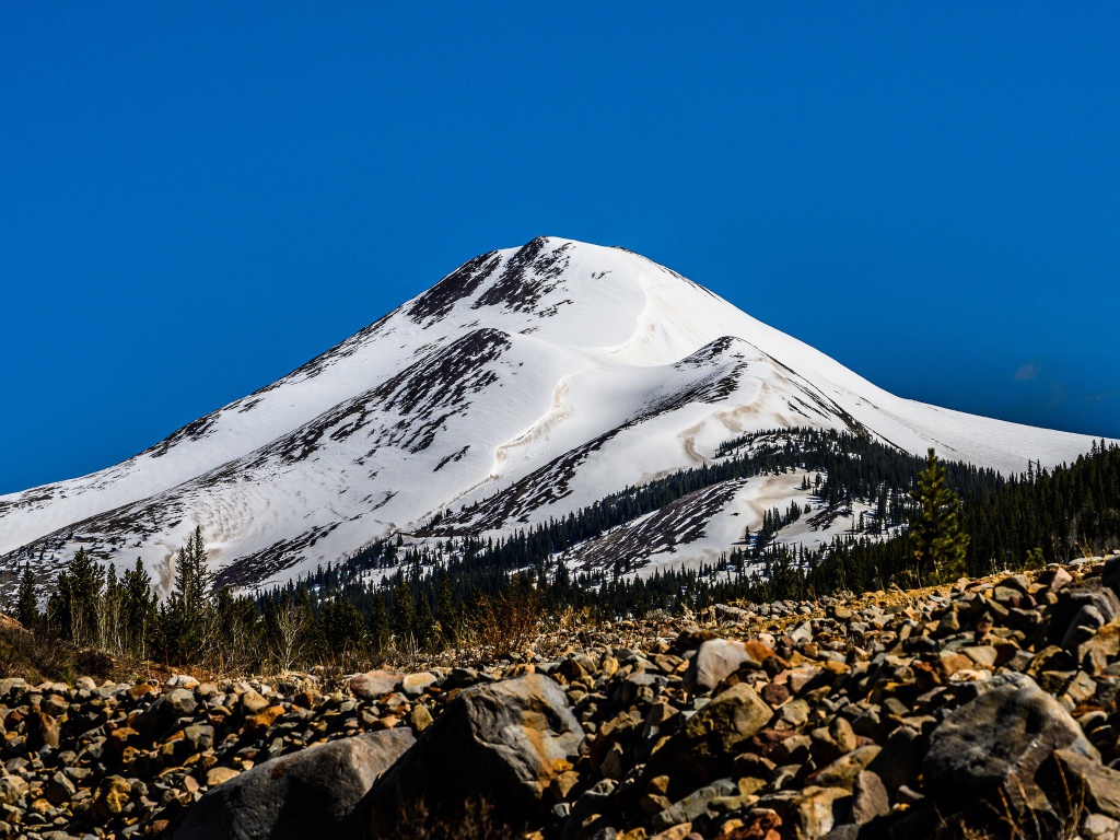 Высокая заснеженная гора под голубым небом