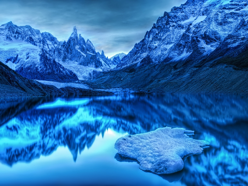 Snow-capped mountains reflected in the water at dusk
