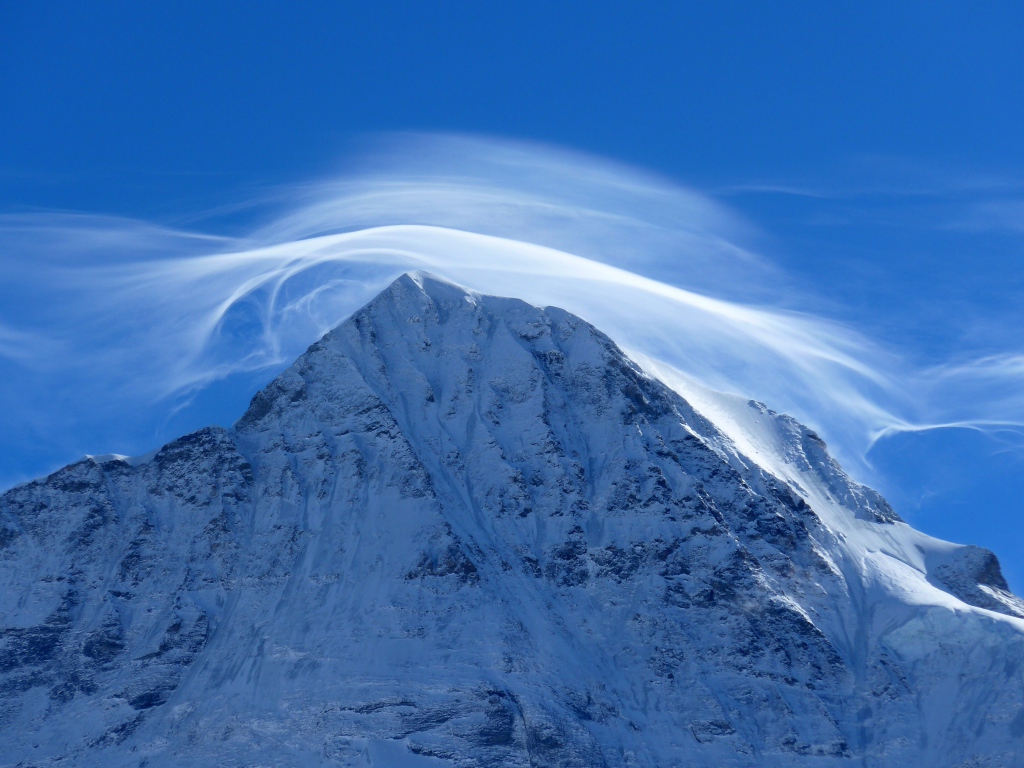 White cloud in blue sky over snowy mountain peak