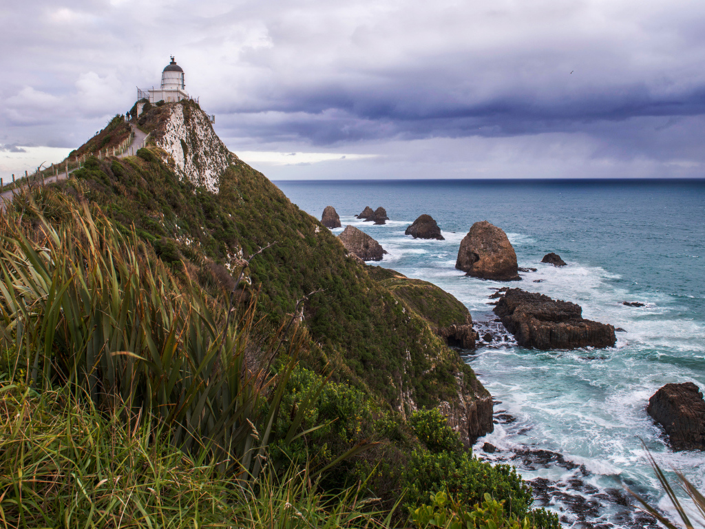 Маяк на вершине утеса у моря под грозовым небом