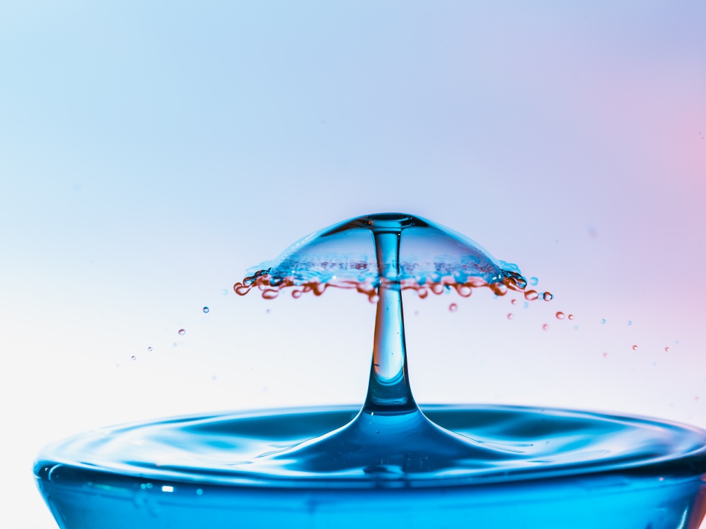 Зонтик из воды в стакане на сером фоне