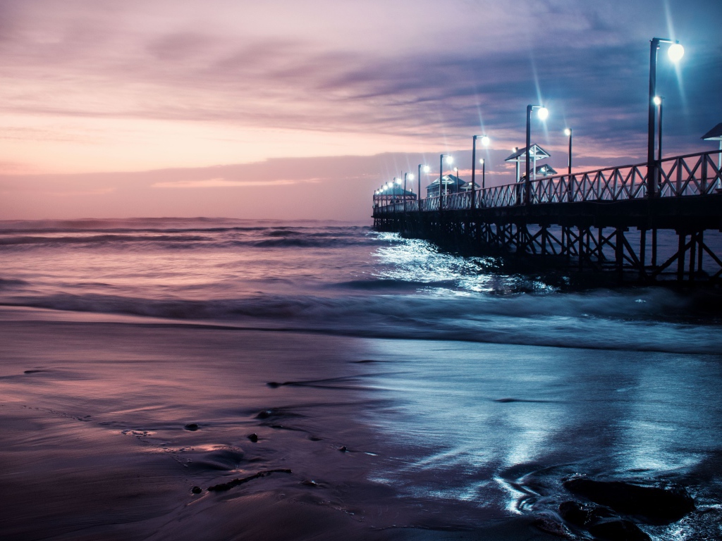 Вид на мост в океане с включенными фонарями ночью