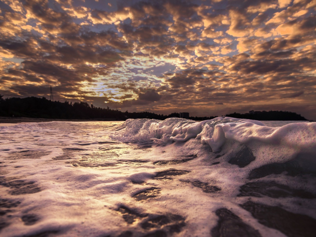 Белые волны на песке на рассвете 