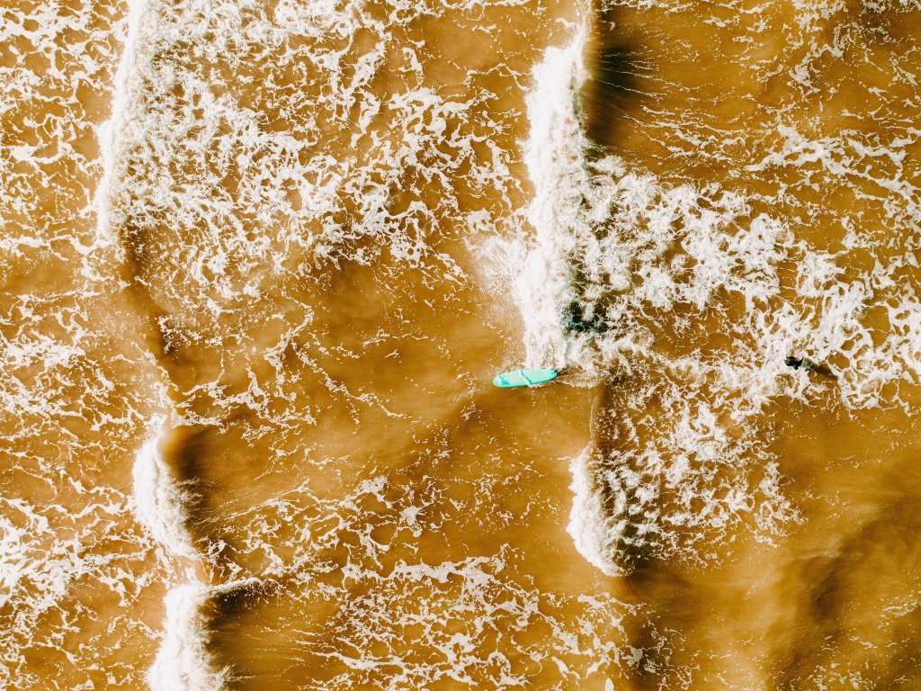 Белые волны на воде поднимают песок