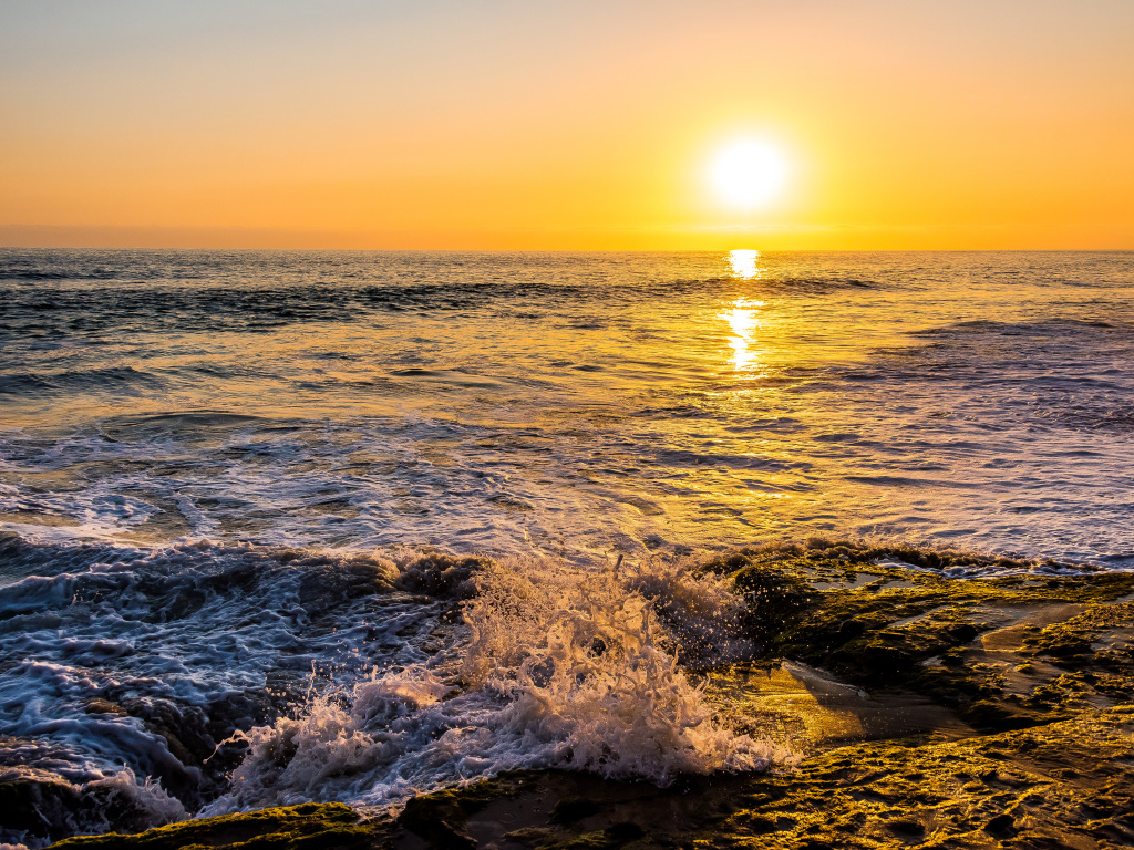 Белые волны бьются о берег на закате 