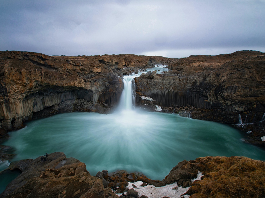 Красивый водопад стекает с каменной скалы в озеро 