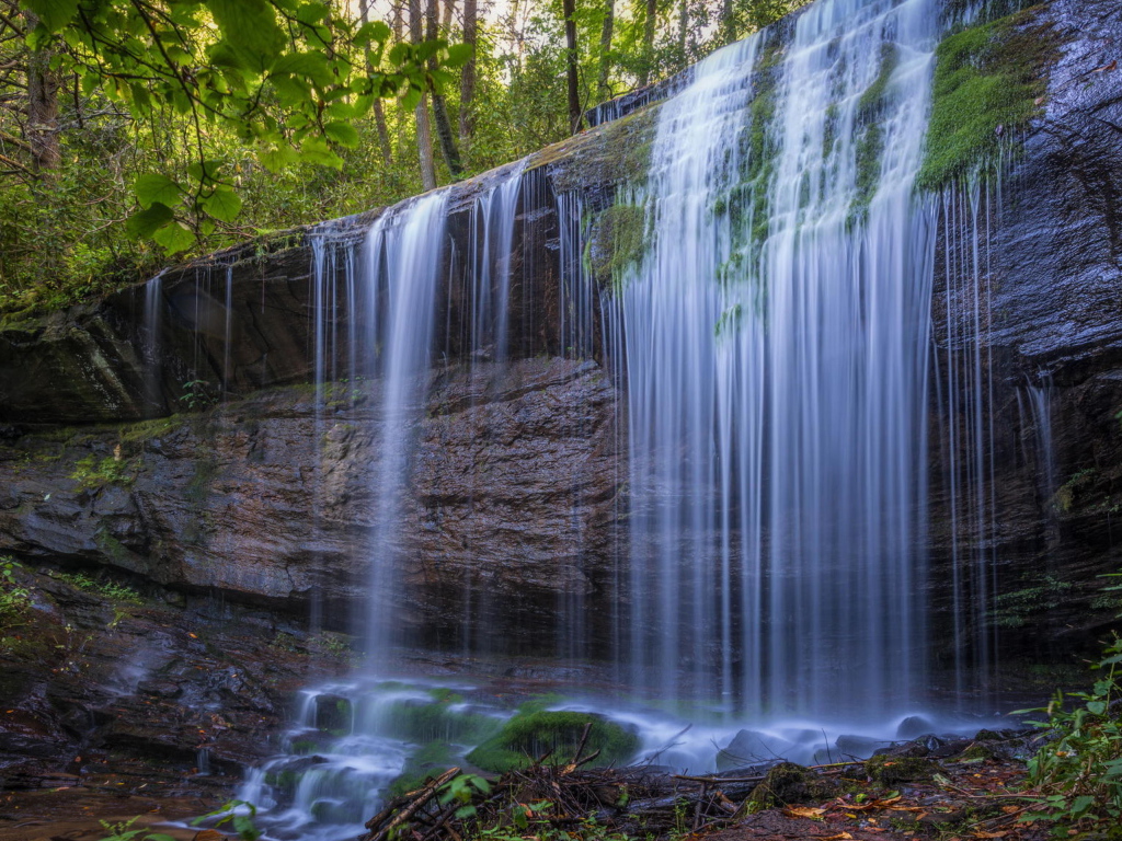 Холодная вода водопада стекает по мокрой скале