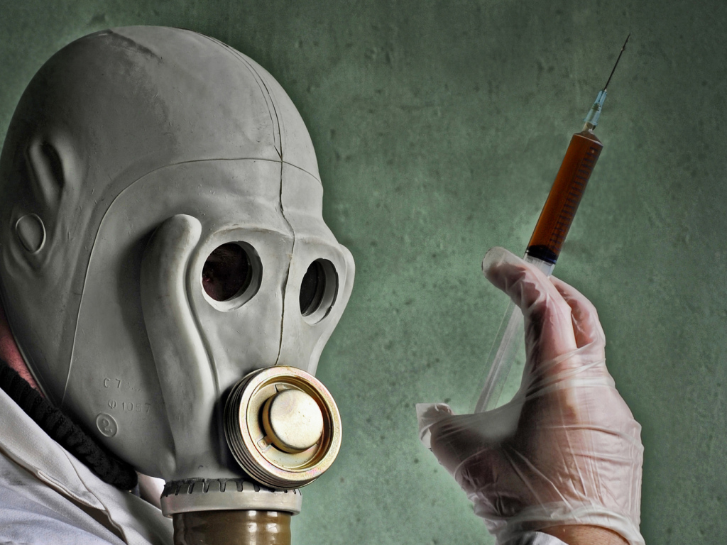 Мужчина в противогазе со шприцем в руках, пандемия коронавирус