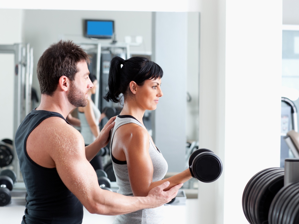 Девушка занимается в спортзале с тренером