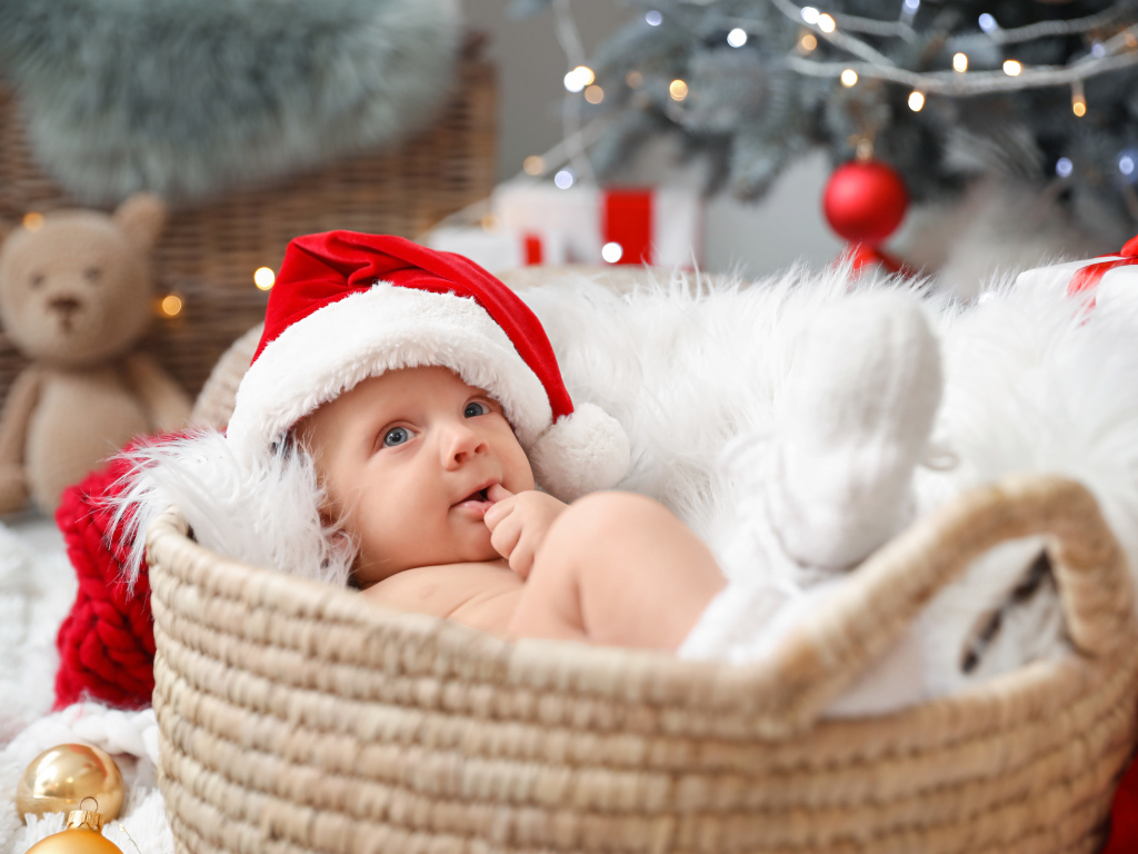 Милый малыш в шапке Санта Клауса лежит в корзине