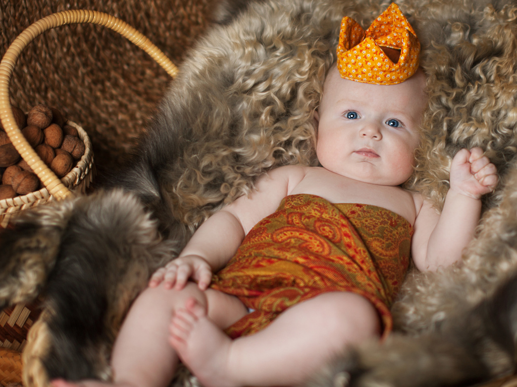 Маленький грудной ребенок в короне лежит в корзине 