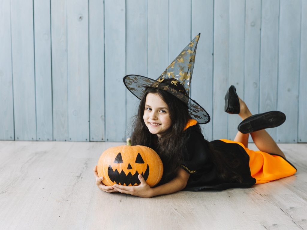 Маленькая девочка в костюме ведьмы с тыквой на Хэллоуин