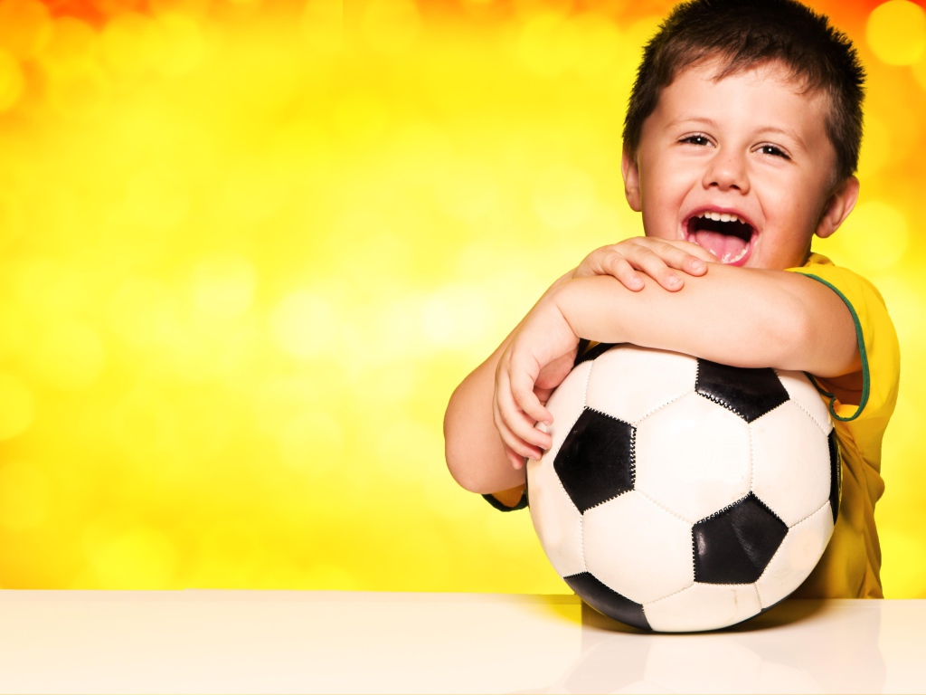 Маленький довольный мальчик с футбольным мячом