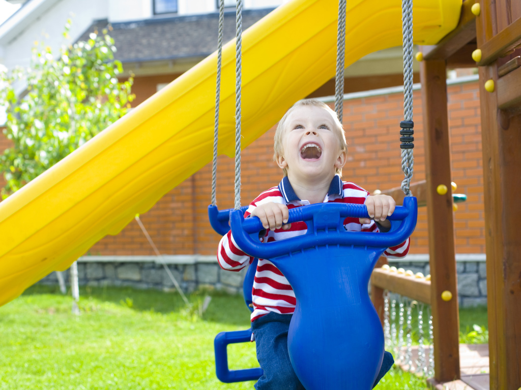 Улыбающийся ребенок на качели 