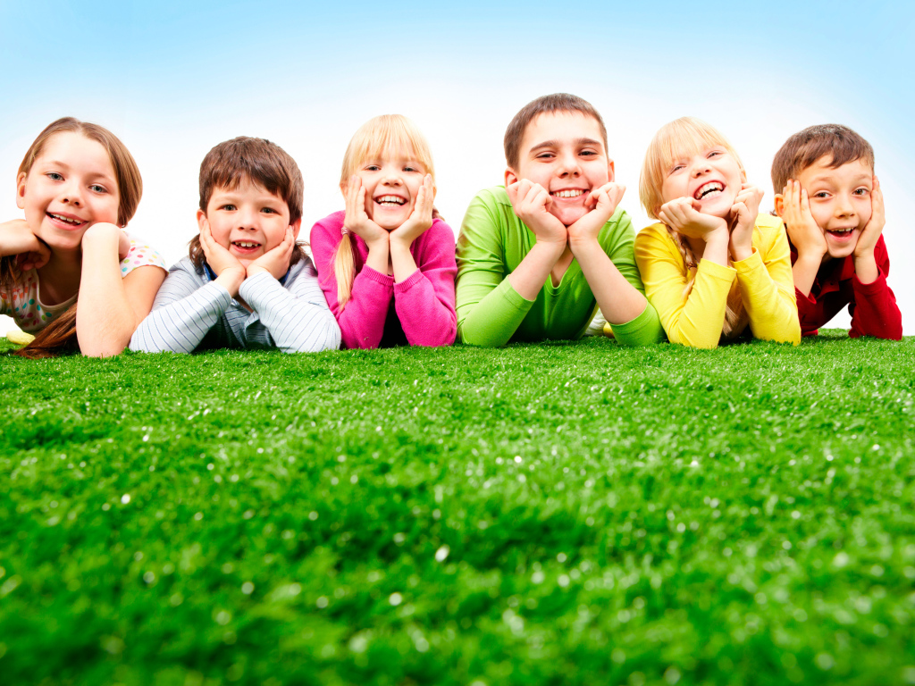Улыбающиеся дети лежат на зеленой траве
