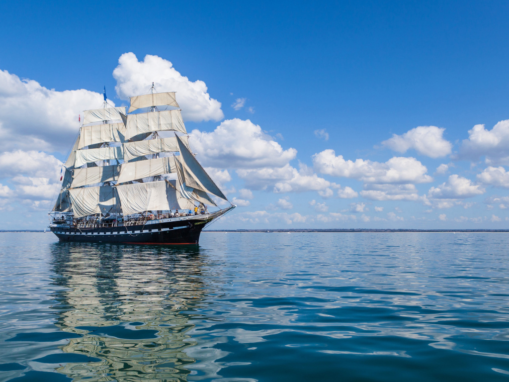 Большой парусный барк в небе над морем с белыми облаками 