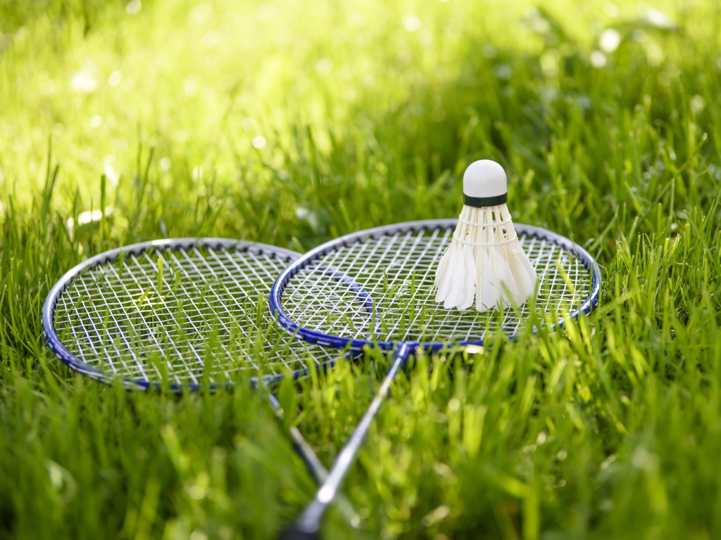 Shuttlecock and badminton rackets on green grass