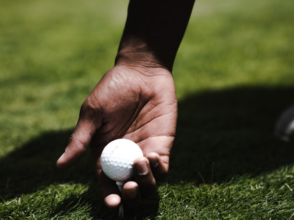 White golf ball in a man’s hand on the field