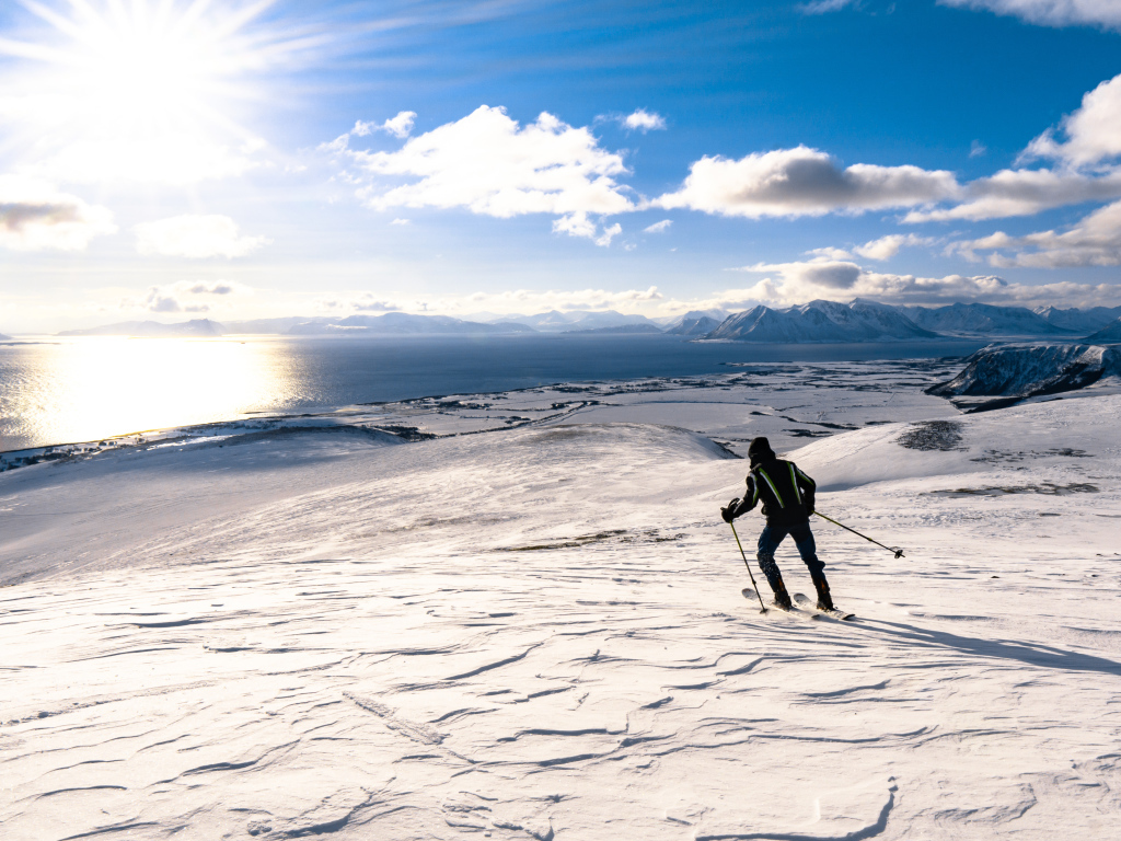 Лыжник едет по снегу под ярким солнцем у воды