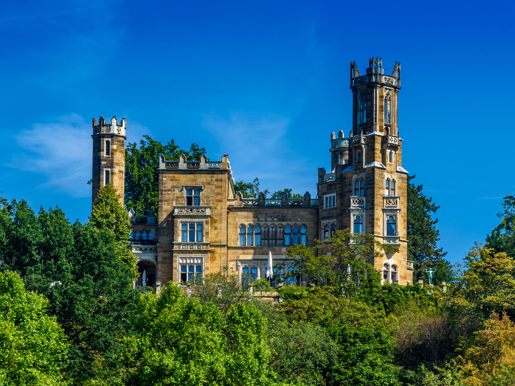 Старинный замок в зарослях деревьев на фоне голубого неба, Германия