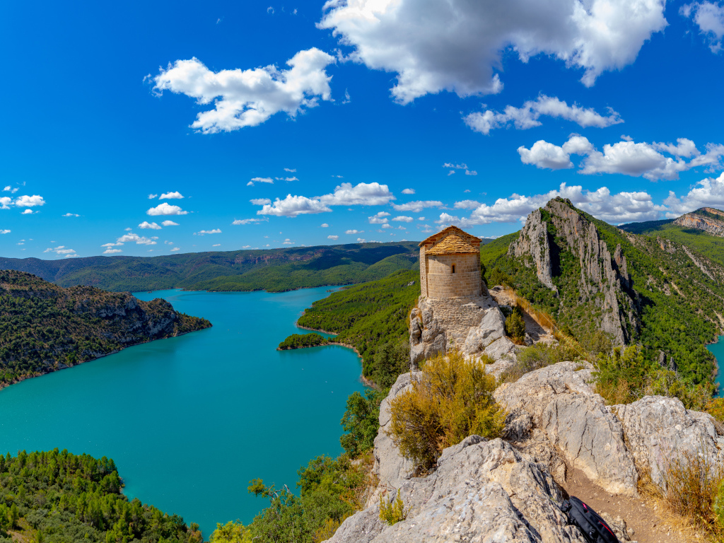 Старое здание на вершине утеса на фоне реки под голубым небом, Испания 