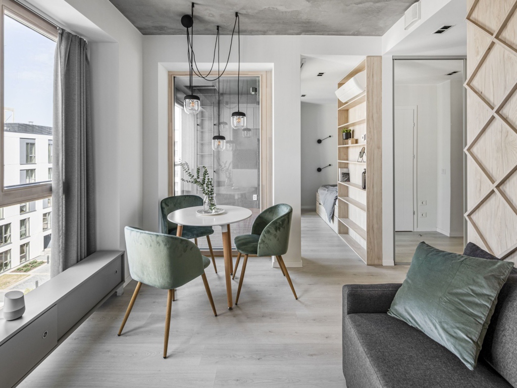 Стол  с креслами стоит у большого окна в квартире 