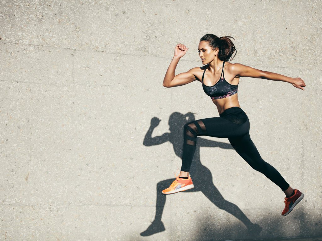 Девушка спортсменка бежит на стадионе 