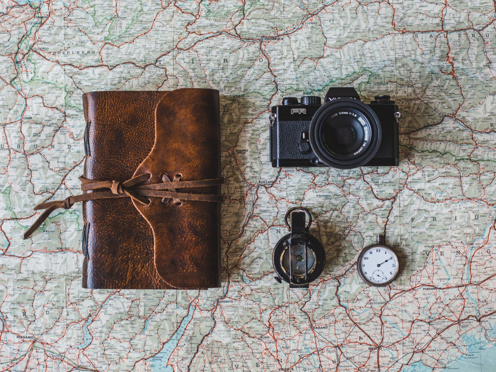 Old camera, compass, clock, notepad and map on the table