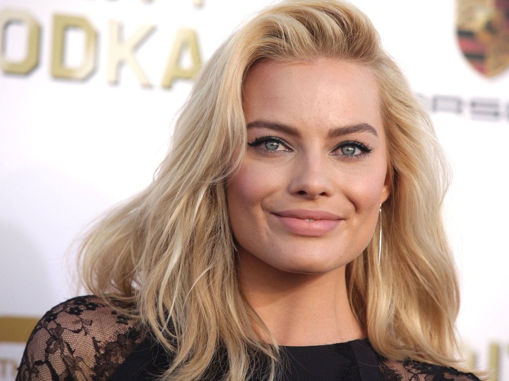 Улыбающаяся блондинка, актриса Марго Робби у стены