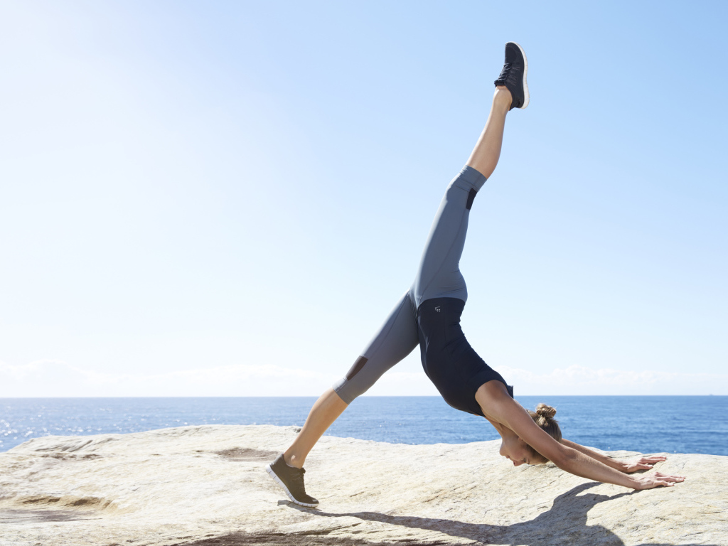 Спортивная девушка делает упражнения на берегу моря 