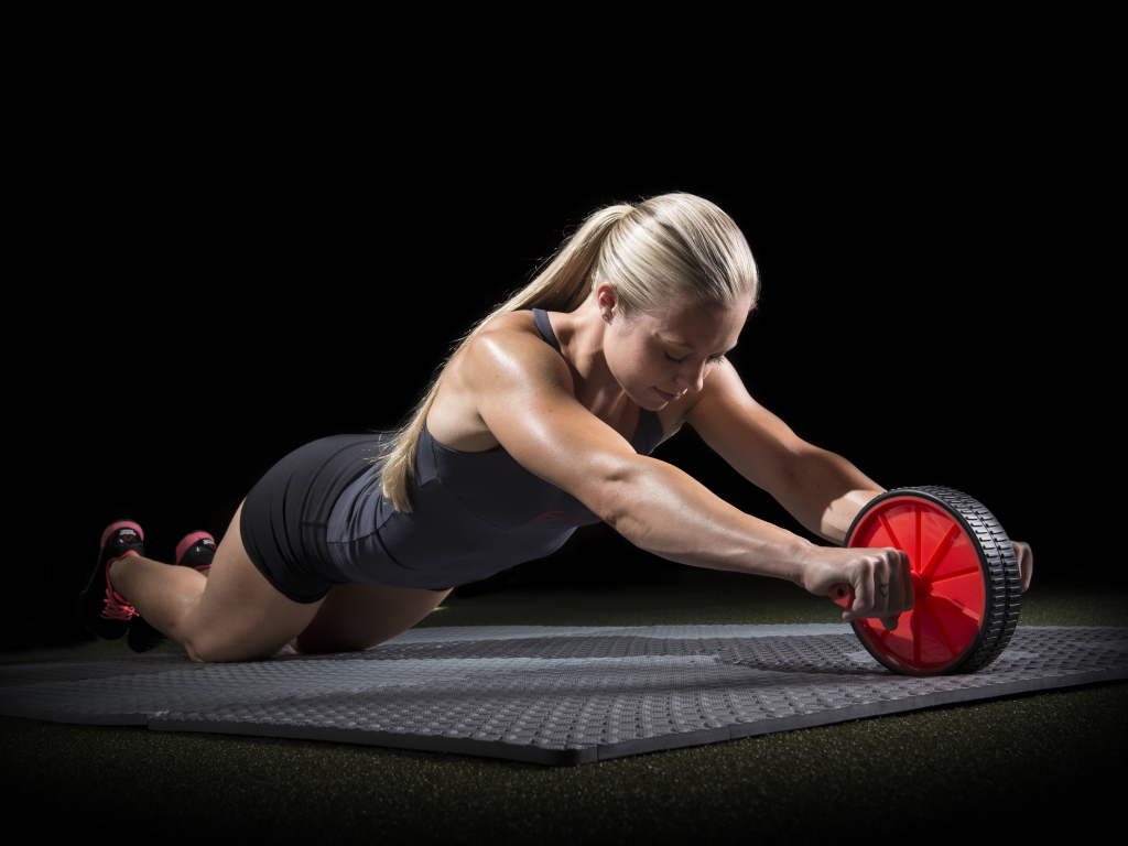 Девушка занимается фитнесом с колесом