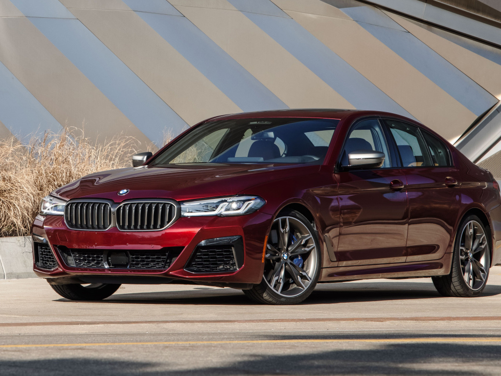 Бордовый седан BMW M550i XDrive, 2021 года у здания