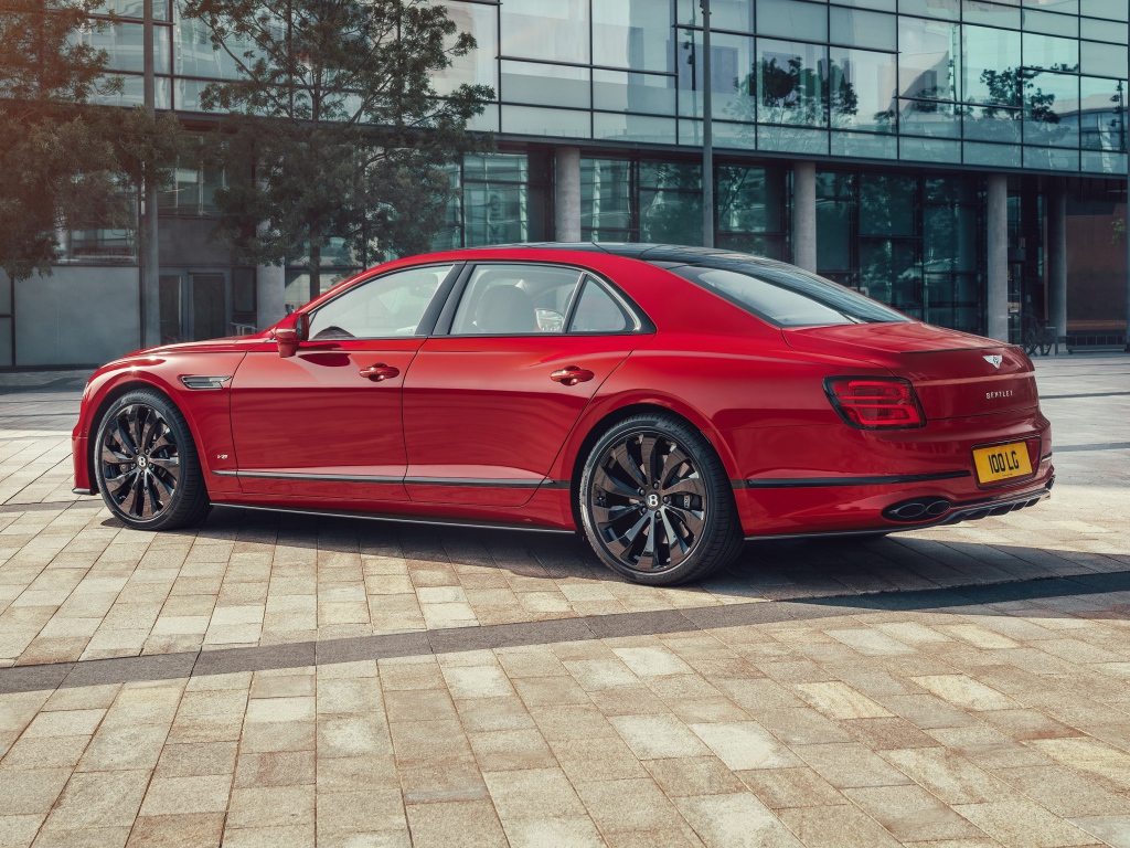 Красный автомобиль Bentley Flying Spur V8 2020 года у здания 