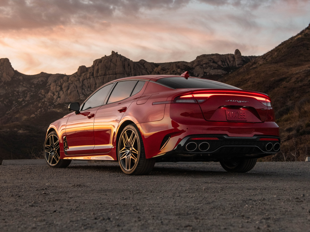 Красный автомобиль Kia Stinger GT, 2022 года в горах вид сзади