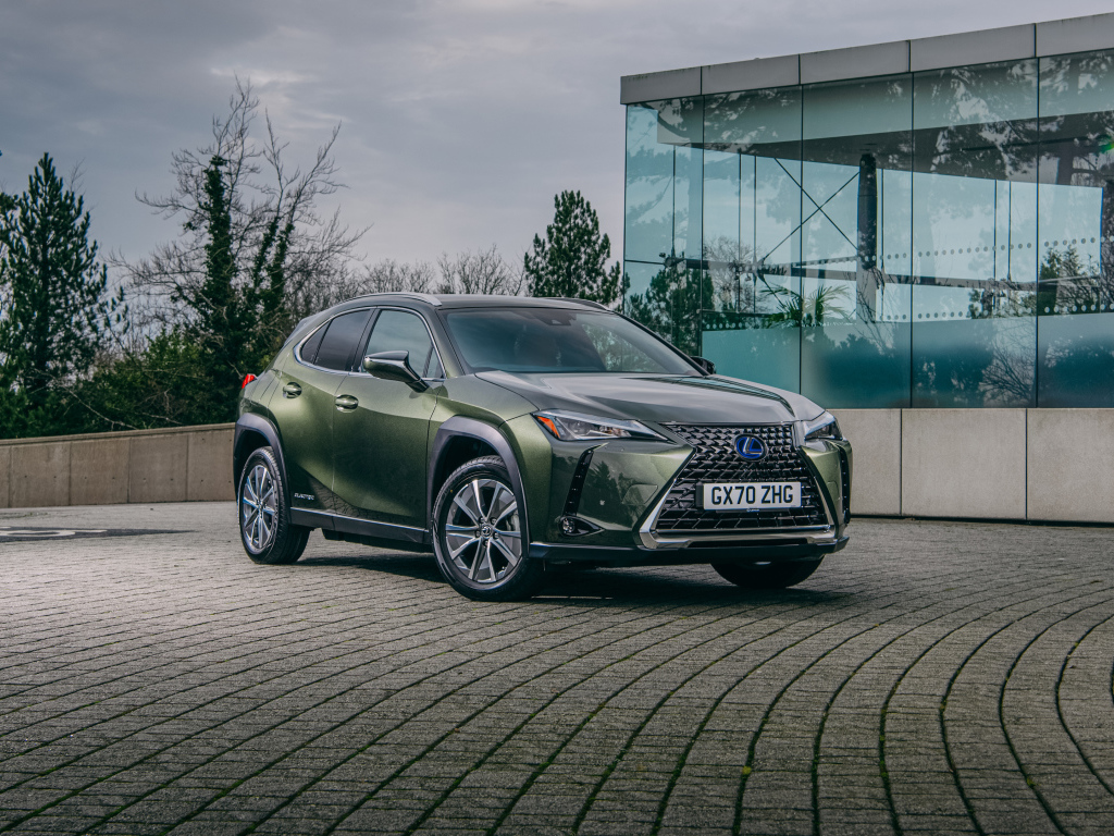 Зеленый автомобиль Lexus UX 300e 2021 года у стеклянной стены
