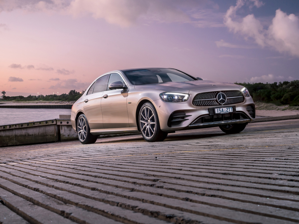 Серебристый автомобиль Mercedes-Benz E 300 E AMG Line 2021 года у реки